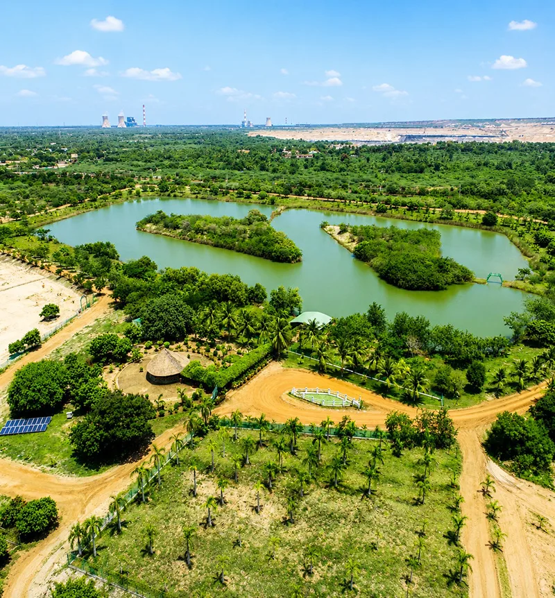 A reclaimed former mine site transformed into a green landscape with lakes, palm trees and solar panels